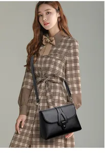 Détail d'un sac bandoulière en cuir grainé noir avec un fermoir pivotant ovale unique