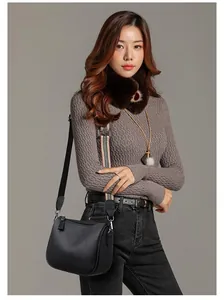 Detail of black pebbled leather saddle bag with striped woven strap and zipper closure