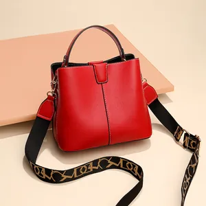 Red pebbled leather bucket bag with artistic woven strap and golden hardware accents