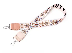Detail of floral embroidery on wide backpack strap with silver metal lobster clasps