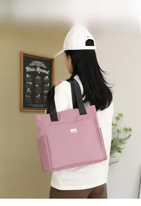 Macro detail of dusty pink tote bag with brand logo and durable nylon handle straps