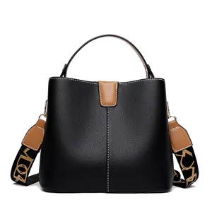 Black pebbled leather bucket bag with brown handles and stylish patterned wide strap