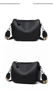 Detail of black pebbled faux leather saddle bag with striped wide shoulder strap