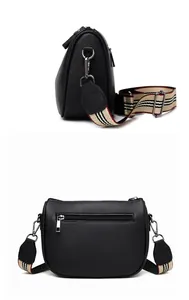 Detail view of black lychee leather saddle bag with striped fabric shoulder strap