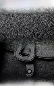 Vue macro détaillée de la texture du cuir noir et du fermoir à pression circulaire