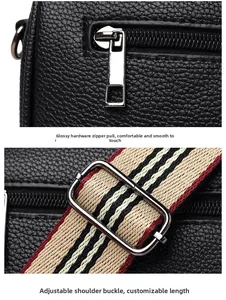 Detail of black pebble leather texture, silver zipper, and striped adjustable strap