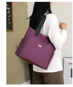 Detail of deep purple waterproof nylon tote bag showing wide black strap and metal logo