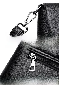 Détails d'un sac en cuir noir avec crochets métalliques et fermetures éclair fluides