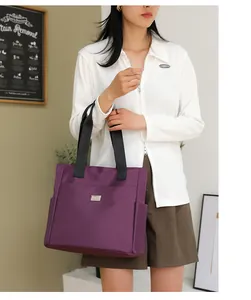 Detail of purple waterproof nylon tote bag with black straps and metal logo plate