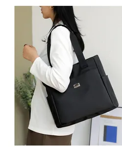 Detail of black nylon tote bag showing side pocket and matte fabric texture
