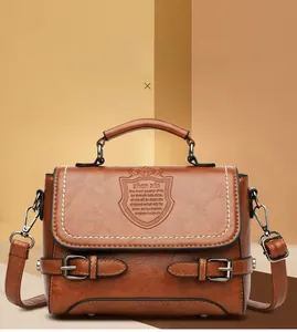 Détail macro du sac en cuir marron avec logo blason gaufré et clous de fond en métal