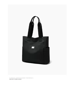 Macro shot of durable black nylon tote bag with metal logo plate and side pocket detail