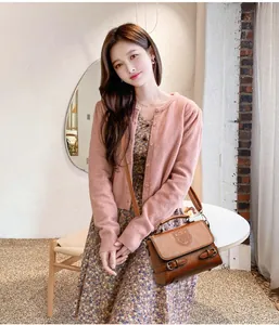 Détail d'un sac bandoulière rétro marron en cuir avec logo bouclier et boucle latérale