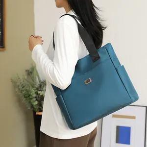 Large teal nylon tote bag for women with durable black straps and spacious compartment