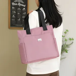 Pink large capacity tote bag with black handles shown on a model in a minimalist room
