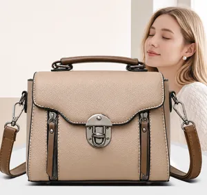 Detailopname van beige crossbodytas met litchi-leertextuur en metalen draaisluiting