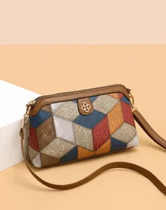 Detail view of colorful geometric patchwork crossbody bag with metallic clover ornament