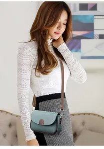 Detail van grijsblauwe crossbodytas van generfd leer met een bruine schouderriem