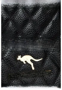 Detailaufnahme aus schwarzem gestepptem Leder mit Litchi-Textur und goldenem Känguru-Logo