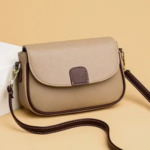 Minimalistische beige crossbodytas met bruine contrastbiezen en gouden hardware