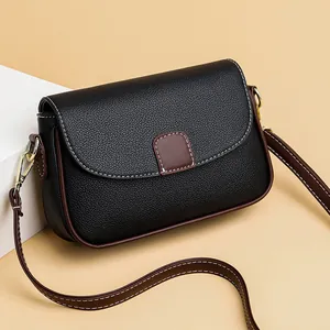 Zwarte crossbody tas van leer met lychee-patroon, bruine rand en gouden hardware