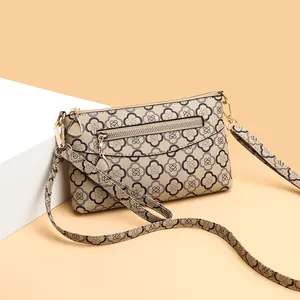 Elegante beige Umhängetasche mit braunem Kleeblattmuster und goldenen Metalldetails