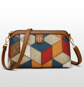 Detail of bohemian crossbody bag showing multicolor geometric leather patchwork and gold logo