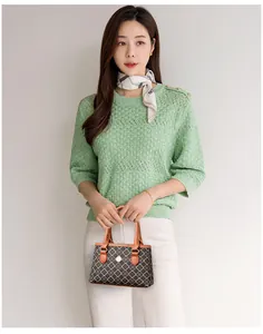 Elegante dunkelbraune Tragetasche mit Kleeblattmuster, präsentiert von einem Model