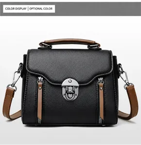 Detail van zwarte lederen crossbody tas met vintage gesp en bruine handvat accenten