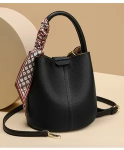 Detail of black pebbled leather bucket bag featuring a silk scarf wrapped handle