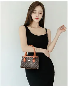Mini-Handtasche mit Kleeblattmuster und orangen Griffen, getragen von einem Model