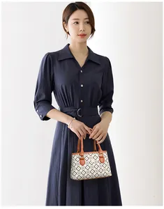 Detail eines eleganten dunkelblauen Hemdkleides mit Taillengürtel und Vintage-Handtasche
