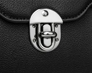 Detail van de gunmetal draaisluiting op een zwarte crossbodytas van generfd leer