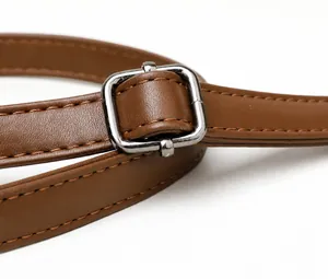 Detail van verstelbare zilveren gesp op de bruine leren riem met strakke stiksels