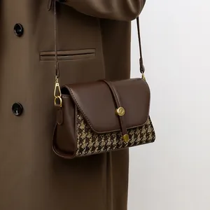 Vintage houndstooth canvas patchwork crossbody bag with gold buckle on brown coat