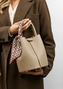 Detailed view of beige grained leather bucket bag with geometric printed silk scarf on handle