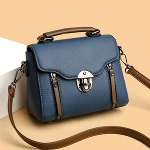 Navy blue crossbody bag with brown handles and pebble leather texture in side view