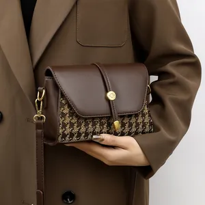 Brown houndstooth canvas and leather crossbody bag with golden metal buckle and strap