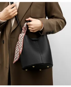 Detail of black lychee grain bucket bag with silk scarf handle and gold bottom studs