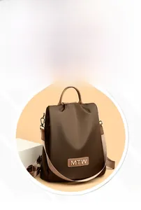 Detail of dark brown Oxford fabric backpack with metal MTW logo and top carry handle