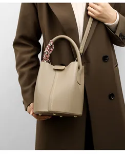 Detailed macro view of taupe bucket bag with lychee grain leather and silk scarf handle