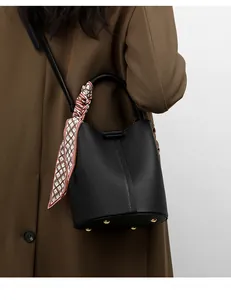 Detail of black pebbled leather bucket bag with silk scarf and gold bottom studs