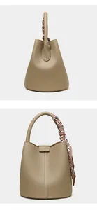 Close-up of lychee grain leather bucket bag with decorative patterned handle silk scarf