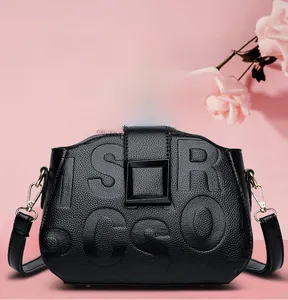 Detail of black lychee grain leather handbag with embossed letters and golden metal hooks