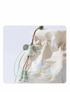 Detailed close-up of a white floral embroidery and jade-like bead pendant on the bag