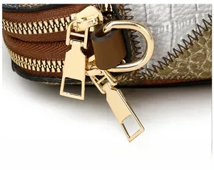 Makro-Detail des goldenen Doppelreißverschlusses und der Krokodil-Prägung am Leder