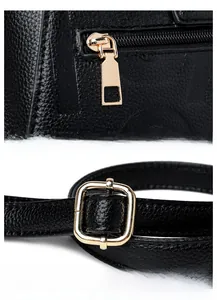 Close-up of black litchi leather bag with gold zipper and adjustable shoulder strap