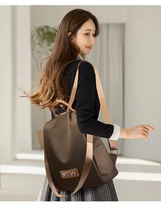 Close-up of the MTW leather label and oxford fabric on a brown women's backpack
