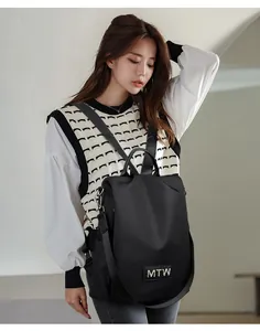 Detail view of the black Oxford fabric backpack showing multi-way straps and the logo.