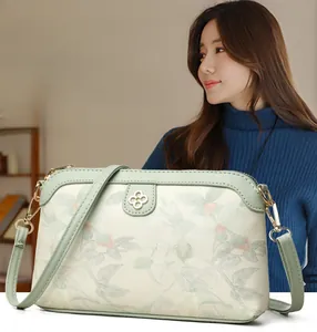 Dettaglio del ricamo floreale e fibbia a quadrifoglio su borsa a tracolla da donna